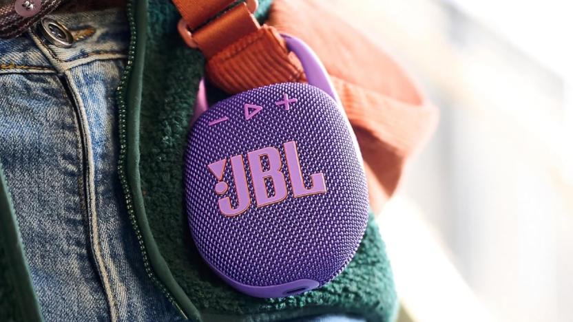 JBL Clip 5 Bluetooth speaker attached to a bag strap.