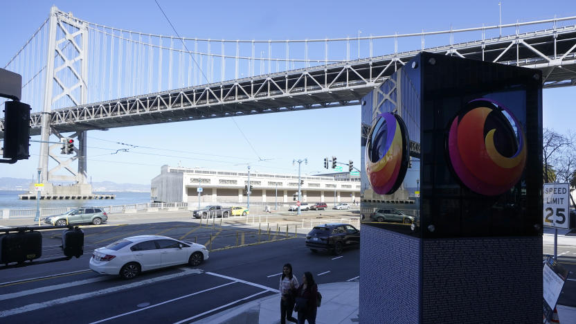 The San Francisco-Oakland Bay Bridge is shown above pedestrians walking next to a Firefox sign at a Mozilla office near the building where a technology executive was fatally stabbed outside of in San Francisco, Wednesday, April 12, 2023. (AP Photo/Jeff Chiu)